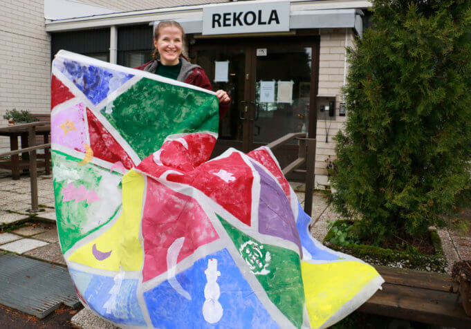 Kulttuuriohjaaja Elina Salmi esittelee vielä keskeneräistä yhteisötaidemaalausta, jonka tekemiseen on osallistunut asukkaita Rekolasta, Pentorinteestä, Rikun ryhmäkodista ja Kukkiakodosta.