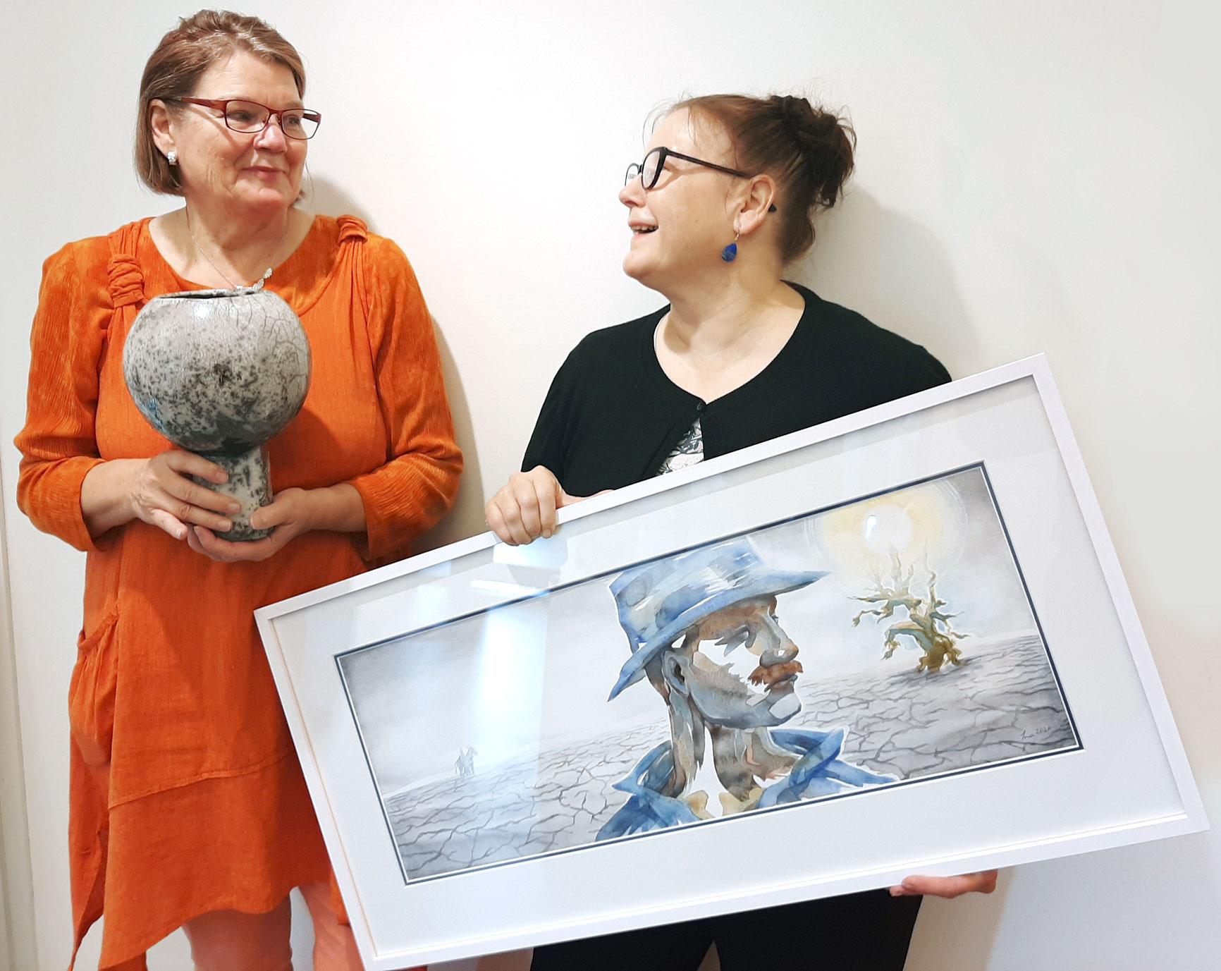 Liisa Turunen ja Ina Jaakkola sanovat olevansa sielunsiskoja. Turusella kädessään rakutekniikalla toteutettu Kehtolaulu-teos ja Ina Jaakkolalla Vääriä valintoja ja huonoja sattumia 1 -maalaus.