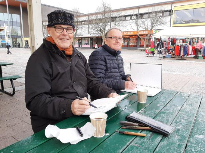Markku Lahtinen ja Olli Mäkelä pitivät kahvitauon näyttelynsä ripustuksen välissä – missäs muualla kuin torikahviossa näkymiä piirrellen.
